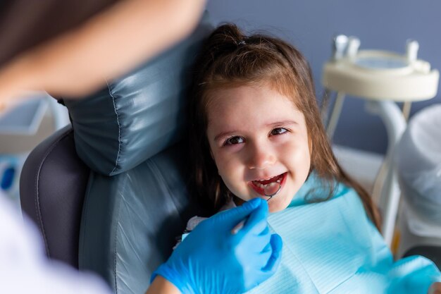 Uma garota sorri enquanto está sentada em uma cadeira de dentista