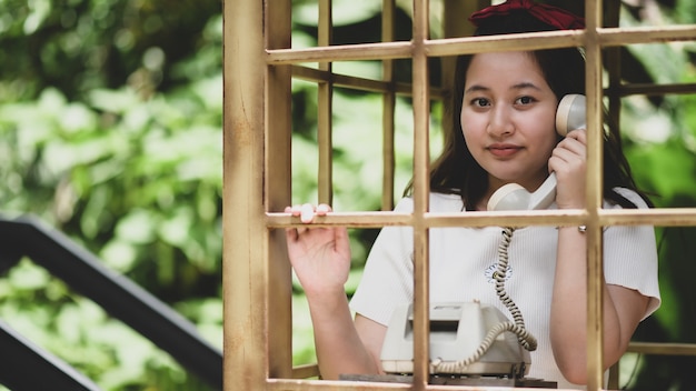 Uma garota sorridente posando com um telefone clássico durante a viagem, ela sorri.