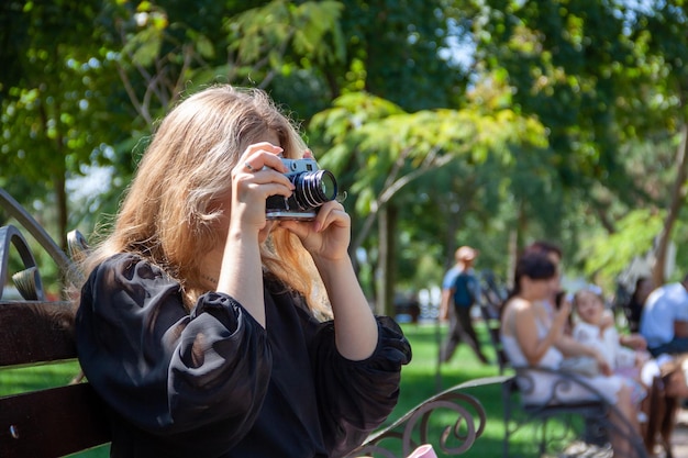 uma garota tira fotos, uma garota usa uma câmera, uma câmera nas mãos, um homem no parque, hobbies, phot