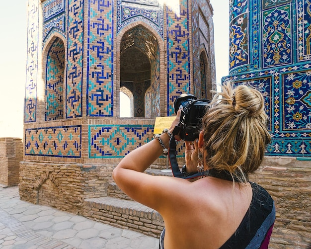 Uma garota turista tira fotos da Madrassa em Samarcanda. Uzbequistão