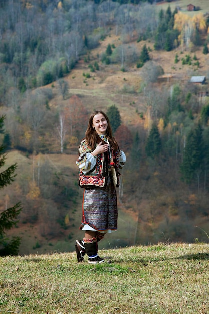 Uma garota ucraniana em um traje nacional Hutsul se posiciona contra o fundo de uma paisagem montanhosa