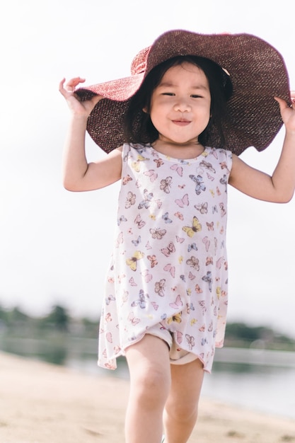 Uma garota usando um chapéu e uma camisa rosa com a palavra praia