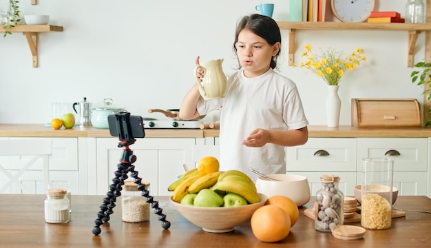 Uma garota vlogger grava conteúdo de vídeo para um blog de culinária uma garota alegre compartilha seus segredos no ar