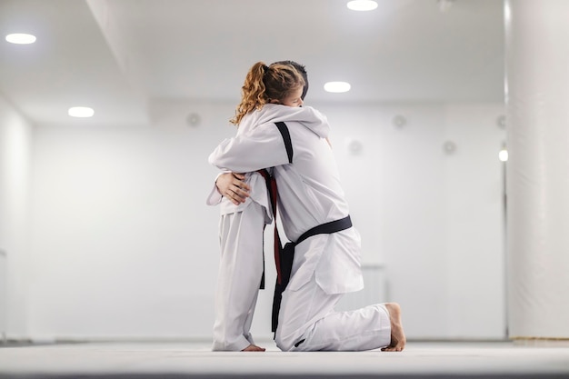 Foto uma garotinha abraça seu treinador na aula de taekwondo na escola de artes marciais