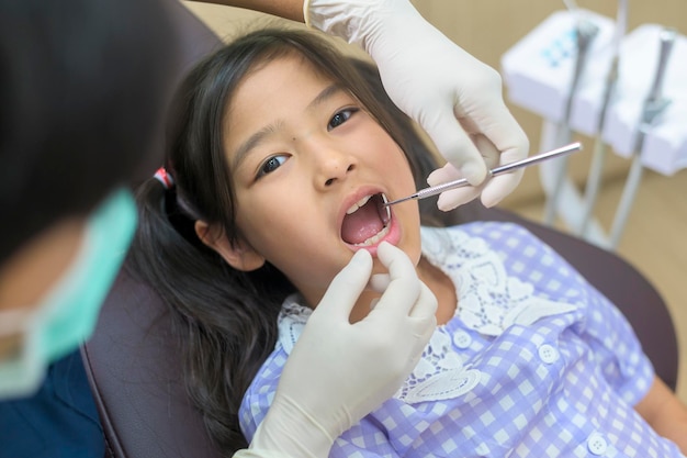 Uma garotinha bonita tendo os dentes examinados pelo dentista no check-up dos dentes da clínica odontológica e conceito de dentes saudáveis