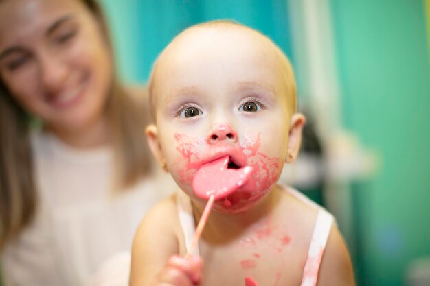 Uma garotinha com cara suja come um doce e olha para a câmera