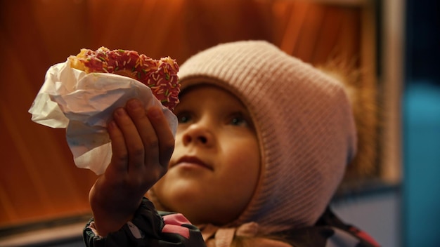 Uma garotinha com roupas de inverno entrega uma rosquinha