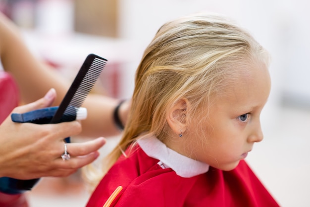 Uma garotinha corta o cabelo no cabeleireiro.