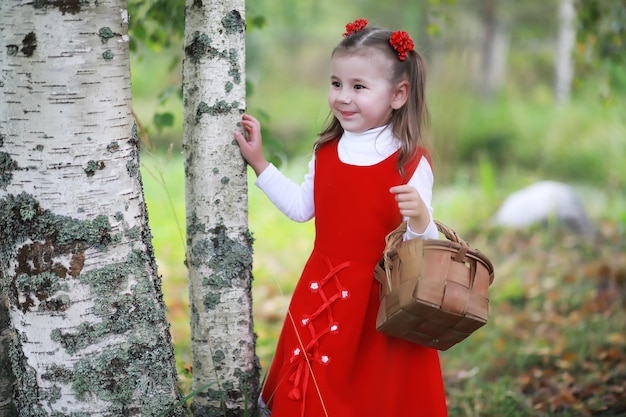 Uma garotinha de chapéu vermelho e vestidos está andando no parque Cosplay para o herói de conto de fadas Chapeuzinho Vermelho