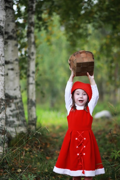 Uma garotinha de chapéu vermelho e vestidos está andando no parque cosplay para o herói de conto de fadas chapeuzinho vermelho