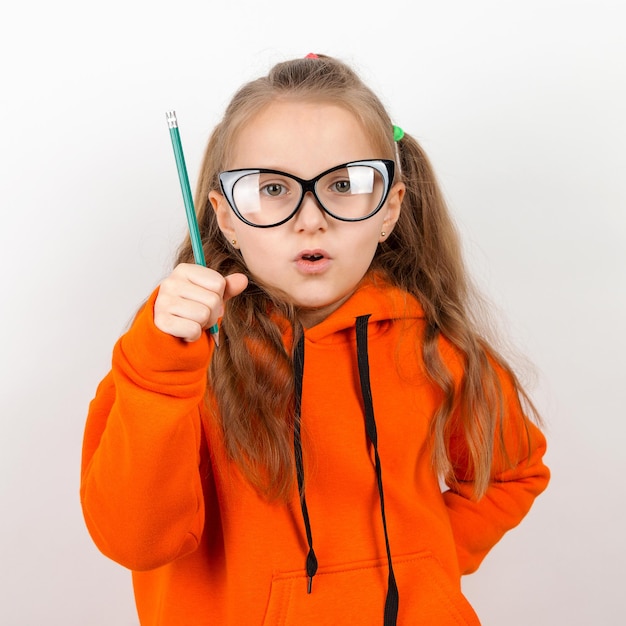 Uma garotinha de óculos e lápis de terno laranja O conceito de autodesenvolvimento de treinamento escolar Em um fundo branco
