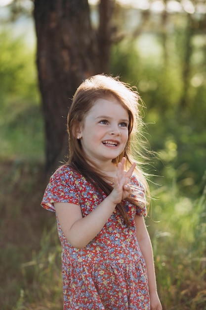 Uma garotinha de vestido branco e sandálias corre ao longo de uma estrada rural Ela tem um brinquedo nas mãos Feliz infância Férias de verão