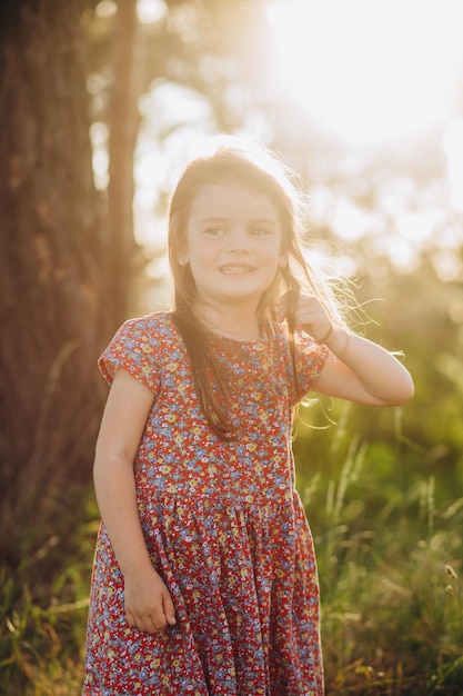 Uma garotinha de vestido branco e sandálias corre ao longo de uma estrada rural Ela tem um brinquedo nas mãos Feliz infância Férias de verão