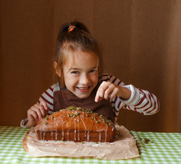 Uma garotinha decora um cupcake e polvilha com sementes na cozinha de casa