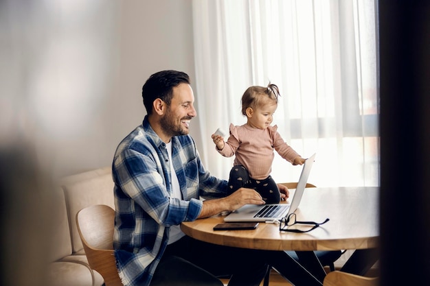 Uma garotinha em cooperação com o pai está terminando o trabalho freelance remoto em casa