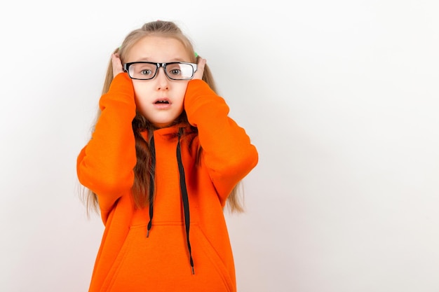 Uma garotinha em um terno laranja e óculos Emoções um retrato em um fundo branco