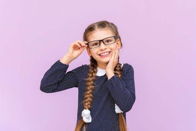 Uma garotinha em um vestido de bolinhas e óculos está muito feliz e sorridente