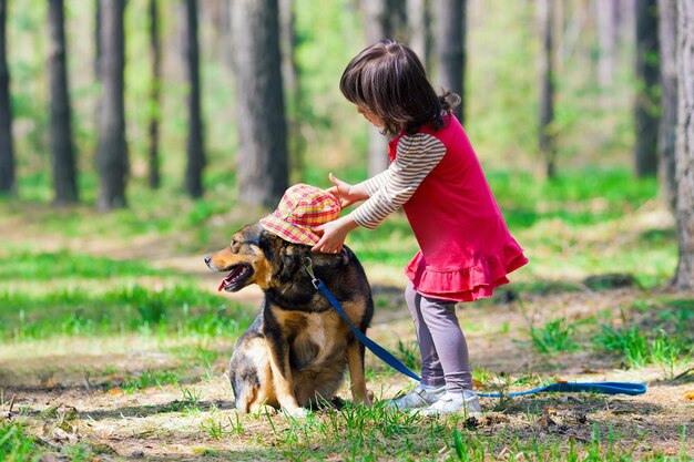 Uma garotinha está acariciando um cachorro na floresta.