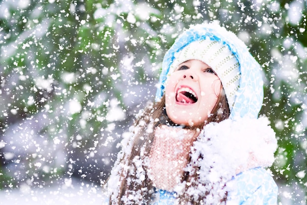 Uma garotinha está pegando flocos de neve com a língua