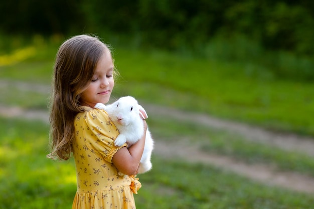 uma garotinha está segurando um coelho branco e olhando para ele com ternura