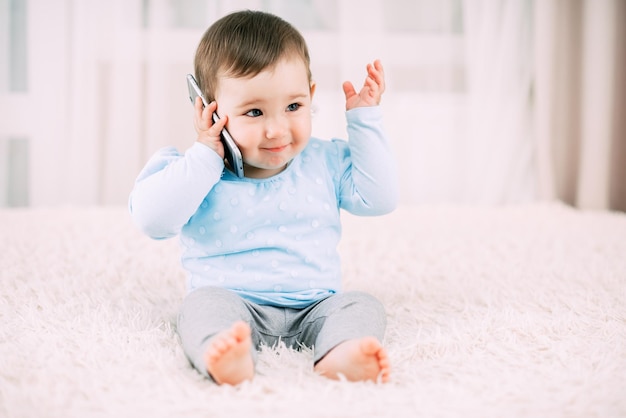 Uma garotinha falando em um smartphone sorrindo e feliz muito doce