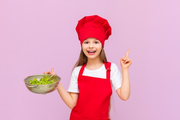 Uma garotinha fantasiada de chef segura uma salada nas mãos e surge com um novo prato de legumes frescos
