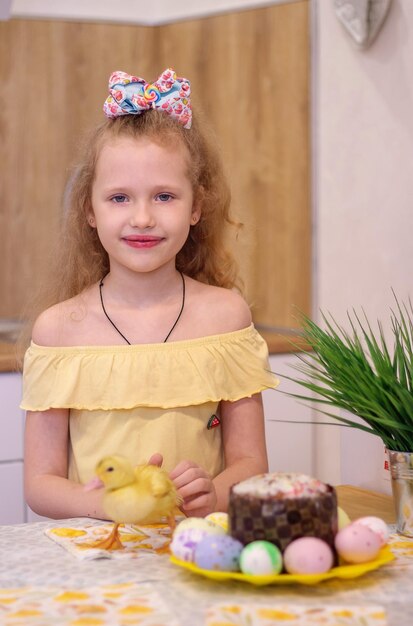 Uma garotinha na páscoa com patinhos amarelos ao lado do bolo e ovos pintados Holiday Family Happiness
