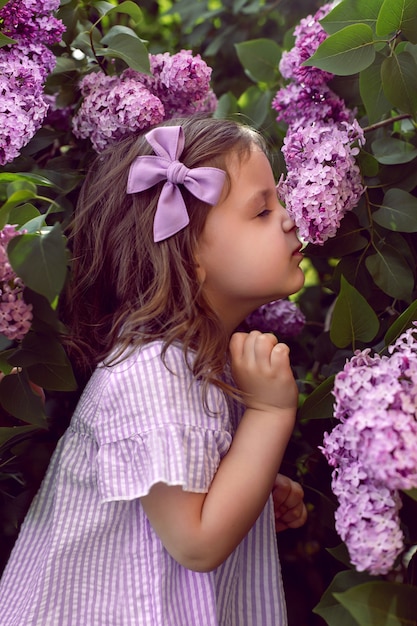 Foto uma garotinha parada em arbustos de lilases