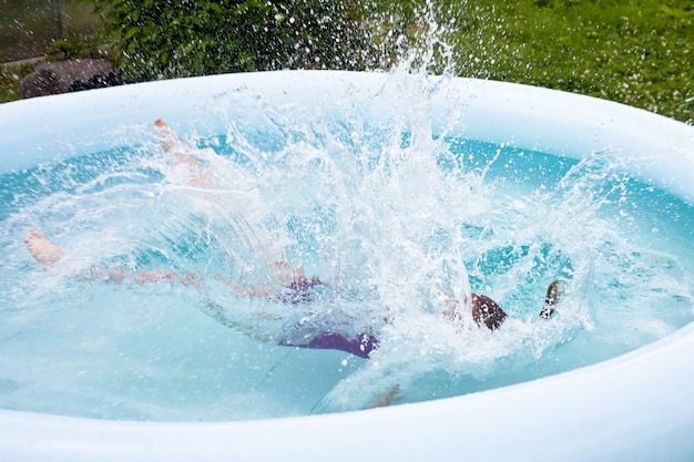 Uma garotinha pula na piscina. Forte espirrando.