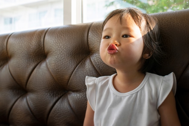 Foto uma garotinha se divertir beijando piadas no sofá