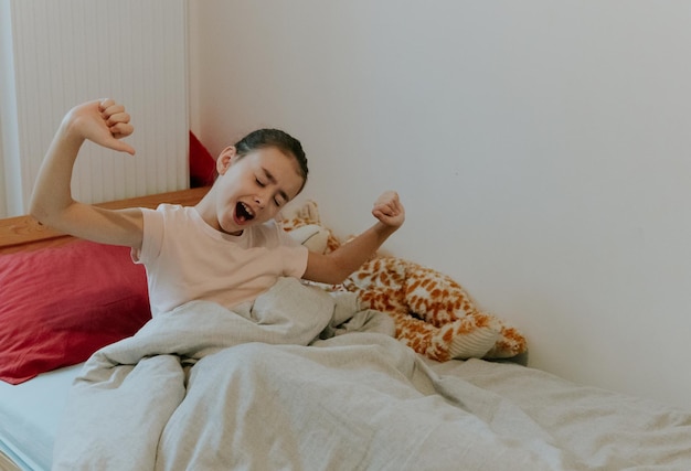 Uma garotinha se levanta na cama pela manhã