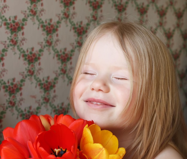 Uma garotinha sorridente com flores de tulipa vermelha e amarela