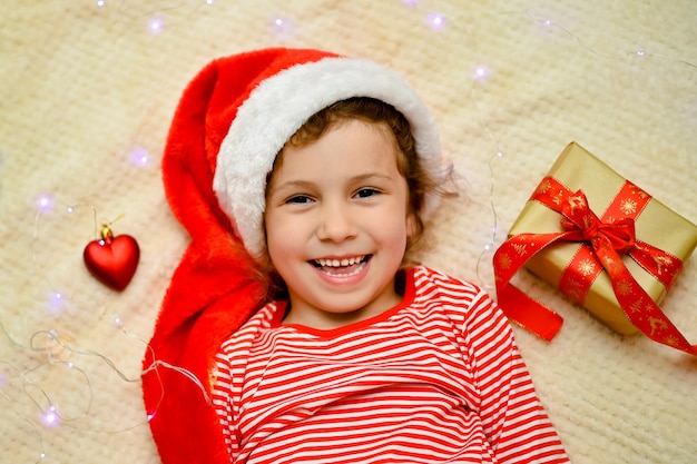 Uma garotinha sorridente no chapéu vermelho do Papai Noel e roupas vermelhas de Natal.