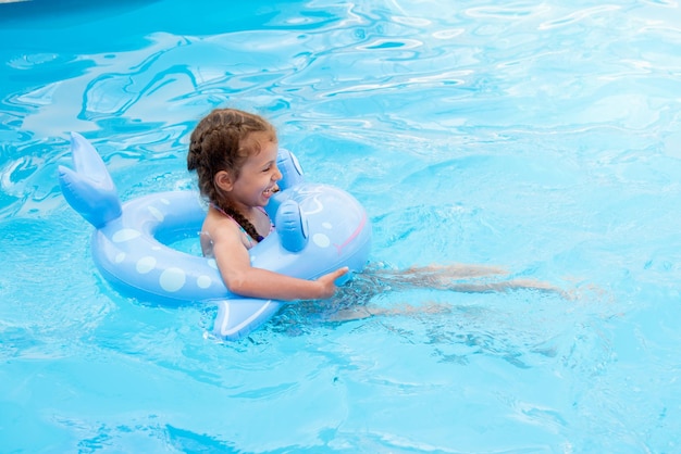 Uma garotinha toma banho na piscina Férias de verão