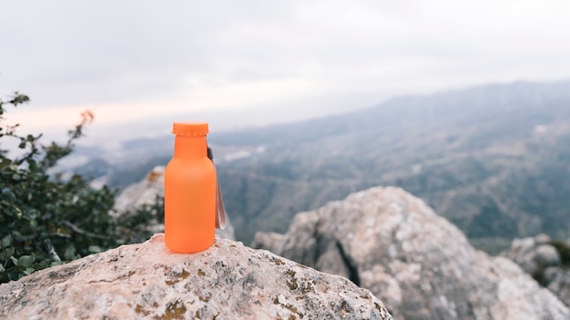 Uma garrafa de água de cor laranja no topo da montanha rochosa