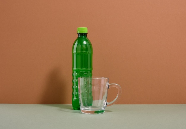 Uma garrafa de água de plástico verde e um copo de vidro Copiar espaço para texto