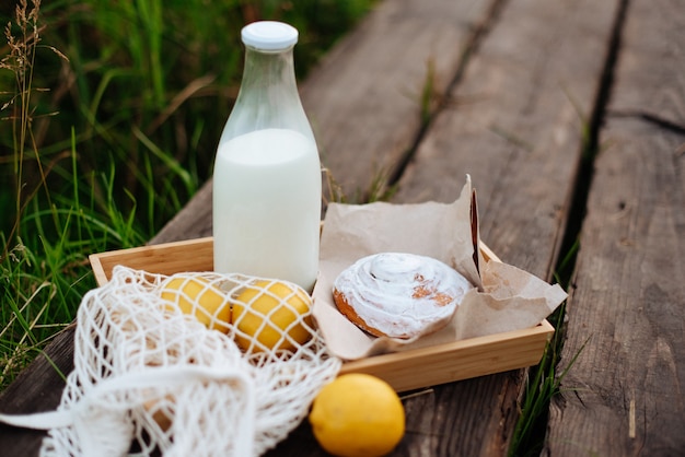 Uma garrafa de leite e um saco de barbante com frutas em tábuas de madeira no lago