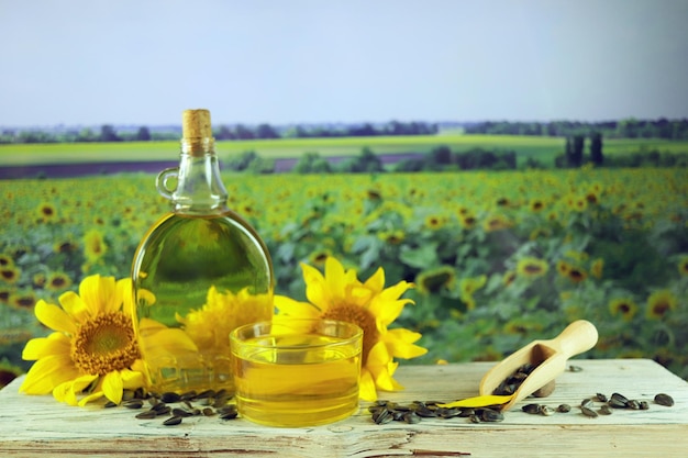 Uma garrafa de óleo, flores frescas de girassol e sementes na mesa, produtos orgânicos, colheita