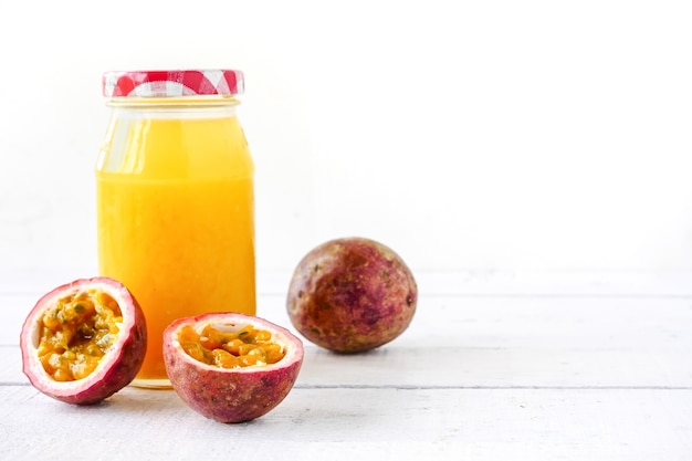 Uma garrafa de suco e maracujá fresco na mesa de madeira. copie o espaço