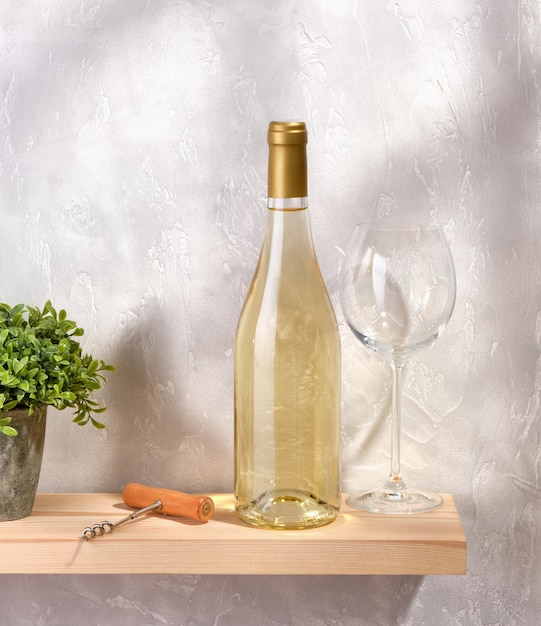 Foto uma garrafa de vinho branco caro um copo bom vazio para bebidas alcoólicas um saca-rolhas para abrir garrafas em uma prateleira de madeira