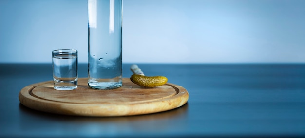 Foto uma garrafa de vodka, um copo e um pepino em conserva