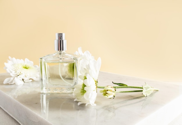 Foto uma garrafa transparente de perfume feminino floral ou água de toalete em um pódio de mármore com flores bege apresentação de fundo publicidade do produto