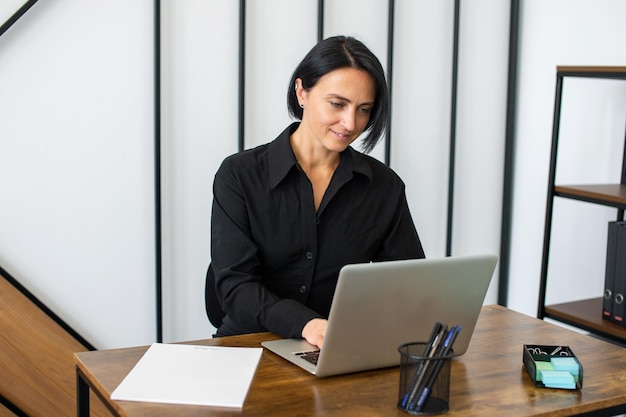 Uma gerente feminina está sentada em uma mesa com um laptop