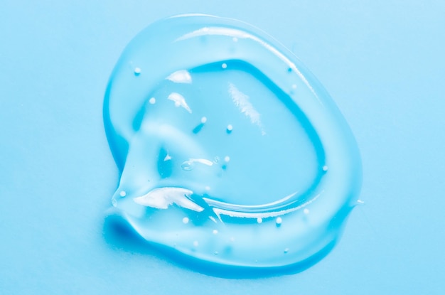 Uma gota de gel líquido ou soro cosmético ou loção de limpeza contra acne Fundo azul