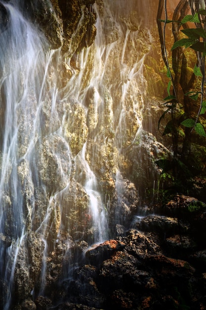 Uma grande cachoeira na selva misteriosa tropical dos raios do sol