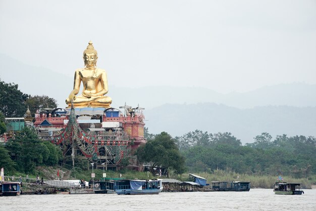 Uma grande estátua de Buda de ouro sentada na frente do grande palco ao lado do rio