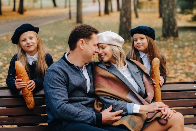 Uma grande família está sentada em um banco em um parque de outono Pessoas felizes no parque de outono