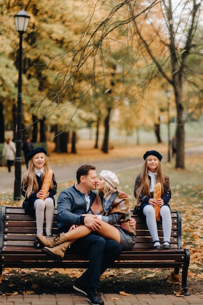 Uma grande família está sentada em um banco em um parque de outono Pessoas felizes no parque de outono