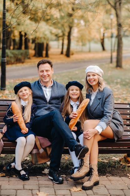 Uma grande família está sentada em um banco em um parque de outono Pessoas felizes no parque de outono