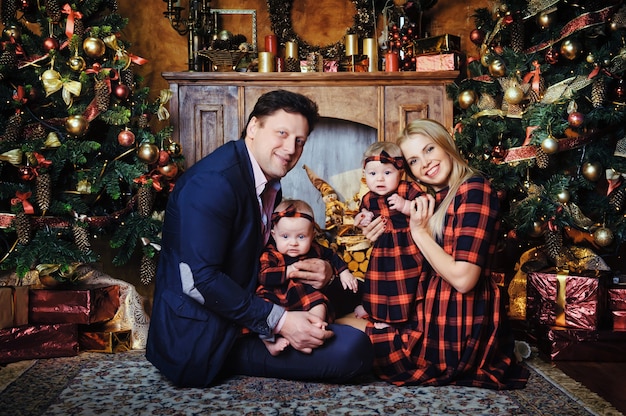 Uma grande família feliz com seus filhos no interior da casa de Ano Novo perto da lareira ao lado da árvore de Natal